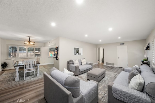 living area featuring recessed lighting, a textured ceiling, baseboards, and wood finished floors