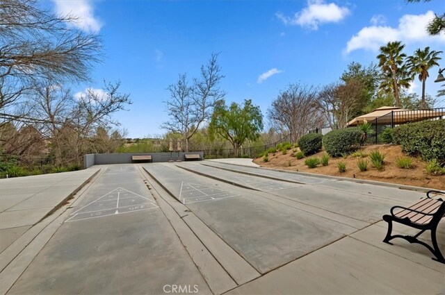 view of property's community with shuffleboard and fence