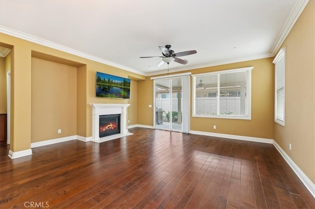 unfurnished living room with ornamental molding, a glass covered fireplace, baseboards, and wood finished floors