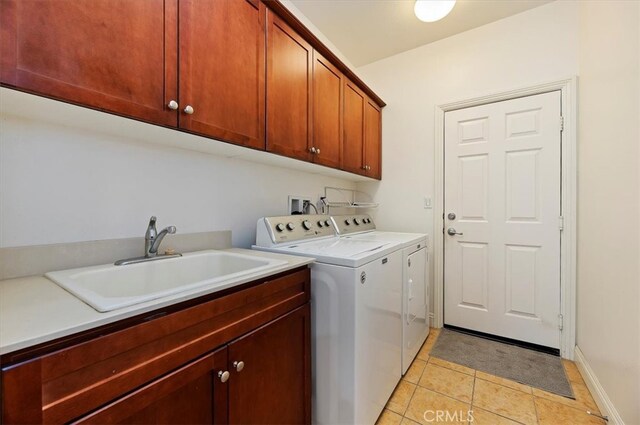 laundry room with light tile patterned floors, cabinet space, a sink, washer and dryer, and baseboards