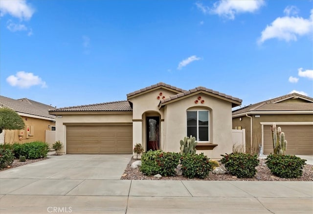 mediterranean / spanish house featuring an attached garage, driveway, a tile roof, and stucco siding