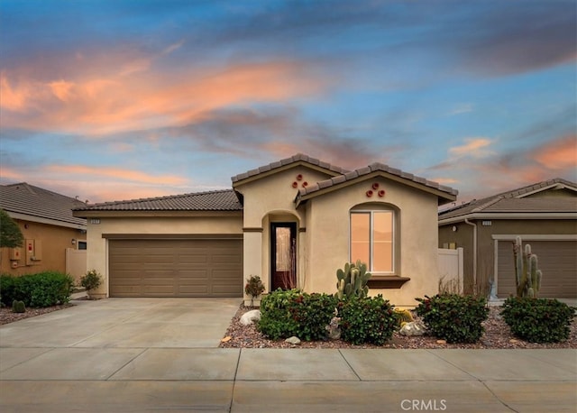 mediterranean / spanish home with a garage, driveway, and stucco siding