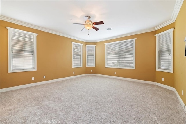 carpeted empty room featuring a ceiling fan, visible vents, crown molding, and baseboards