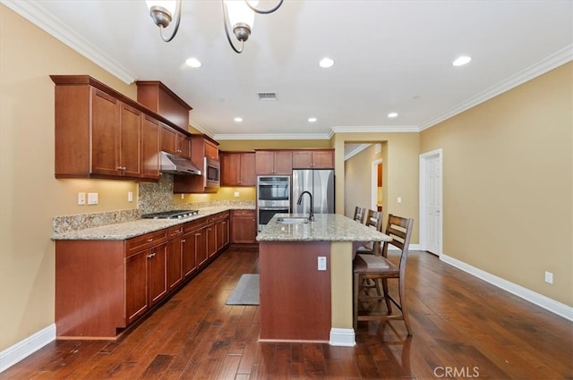 kitchen featuring visible vents, appliances with stainless steel finishes, a kitchen breakfast bar, dark wood-style flooring, and under cabinet range hood