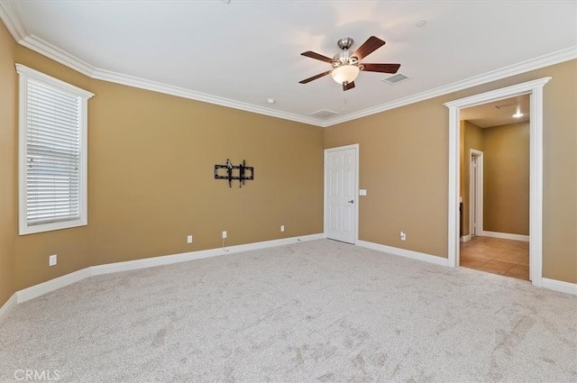 carpeted spare room featuring ornamental molding, visible vents, ceiling fan, and baseboards