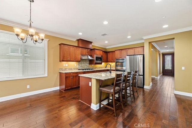 kitchen featuring visible vents, dark wood-style floors, a kitchen breakfast bar, stainless steel appliances, and under cabinet range hood