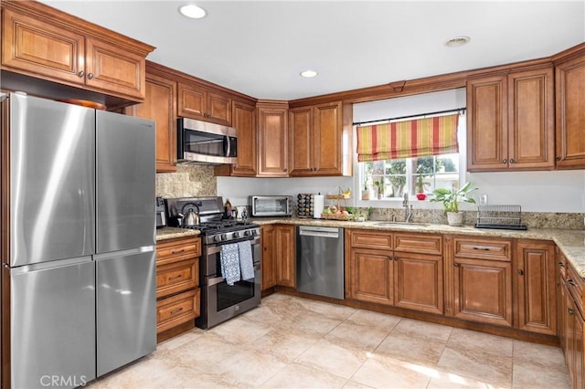 kitchen featuring appliances with stainless steel finishes, a sink, and brown cabinets