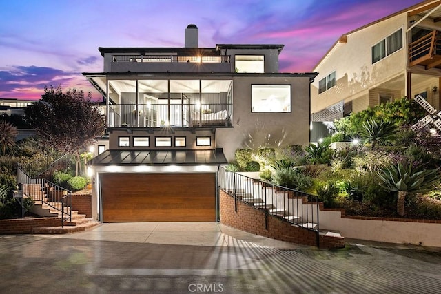 view of front of house featuring stairway, an attached garage, a balcony, and stucco siding