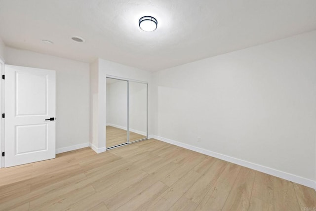 unfurnished bedroom with a closet, light wood-style flooring, and baseboards