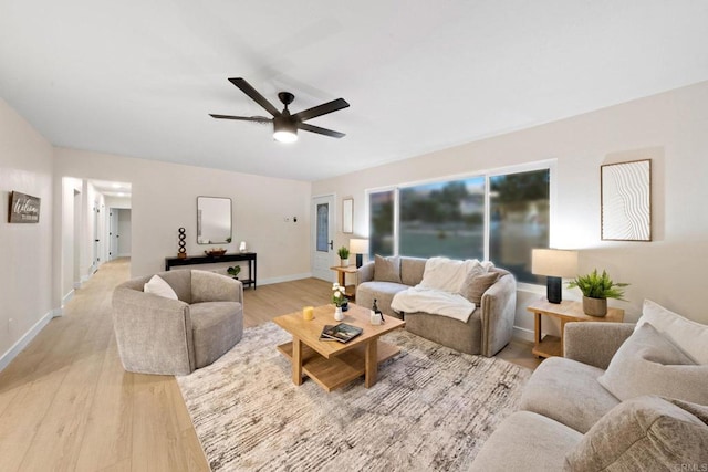 living area featuring ceiling fan, light wood-style flooring, and baseboards