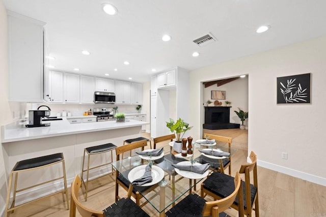 dining room featuring light wood-type flooring, recessed lighting, visible vents, and baseboards