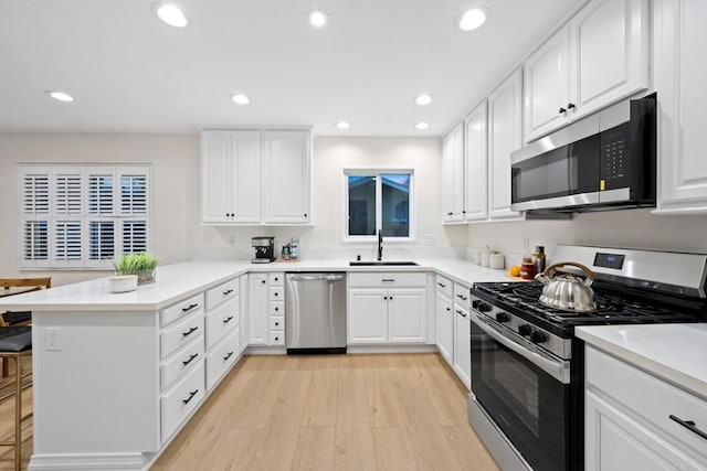 kitchen featuring stainless steel appliances, light countertops, white cabinets, and a peninsula