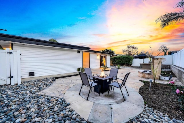 patio terrace at dusk with an outdoor fire pit and a fenced backyard