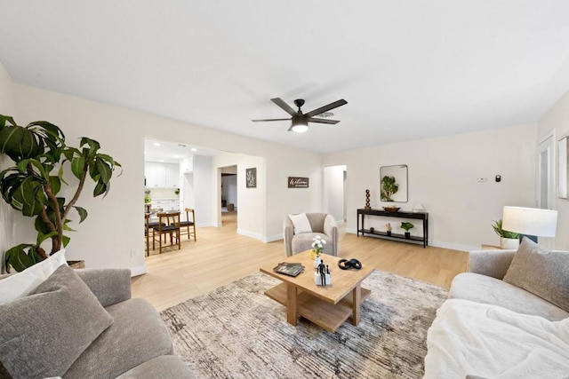 living area with a ceiling fan, light wood-style flooring, and baseboards