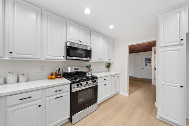 kitchen featuring stainless steel appliances, light countertops, and white cabinetry