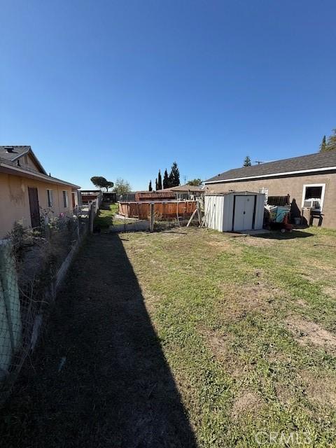 view of yard featuring a storage shed, an outbuilding, and a fenced backyard