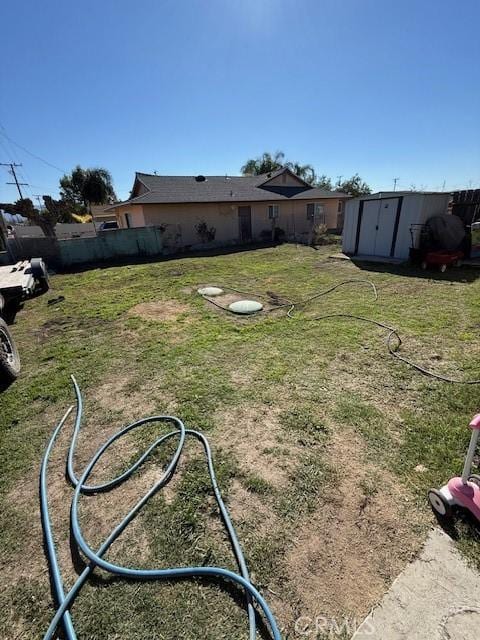 view of yard with a storage shed, an outbuilding, and fence