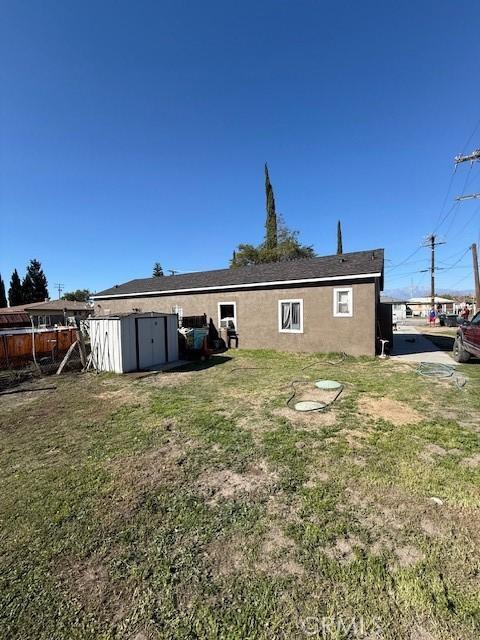 back of house featuring a storage shed, a lawn, and fence