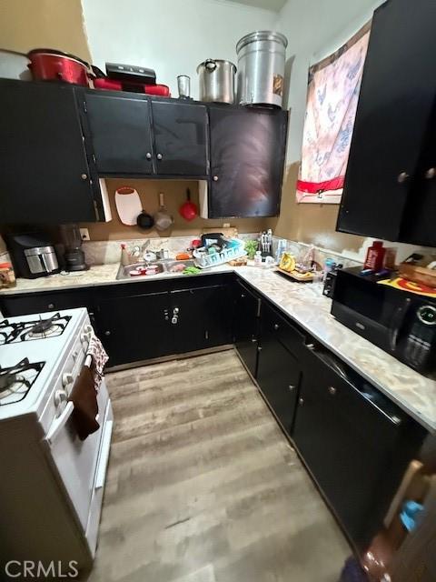 kitchen with gas range gas stove, light countertops, a sink, dark cabinets, and black microwave