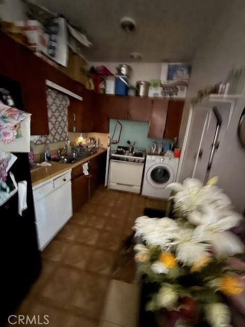 kitchen with white gas range oven, washer / clothes dryer, light countertops, and a sink