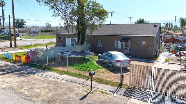 exterior space featuring a fenced front yard, roof with shingles, and stucco siding