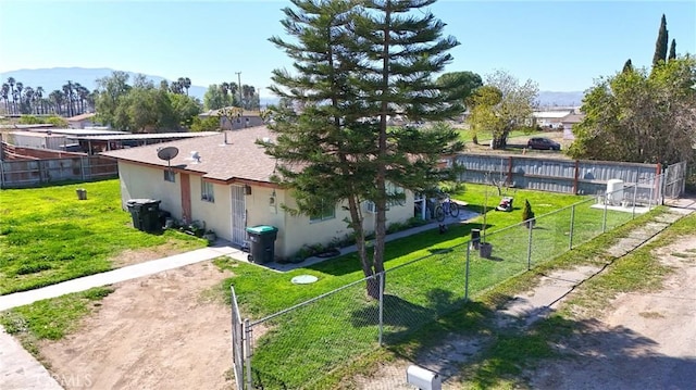 view of side of home featuring a mountain view, a shingled roof, fence, a lawn, and stucco siding