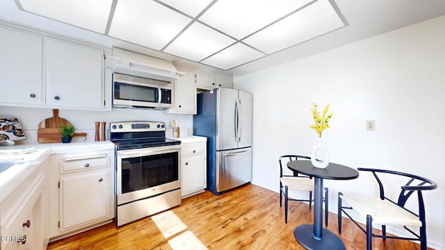 kitchen with white cabinets, light wood-style flooring, stainless steel appliances, and light countertops