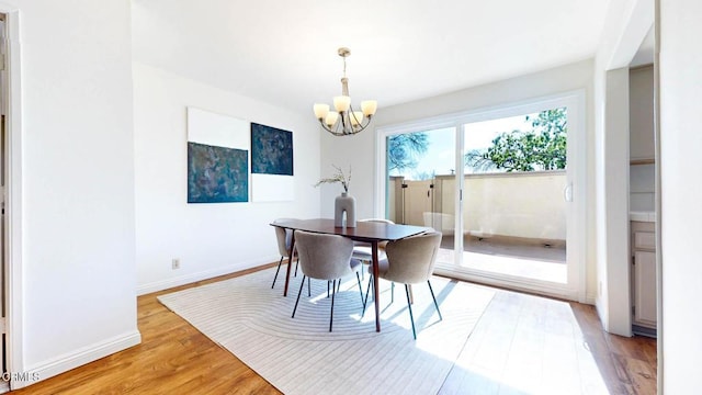 dining space with light wood finished floors, baseboards, and a notable chandelier