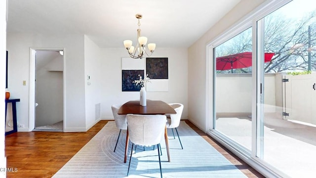 dining space featuring baseboards, wood finished floors, and an inviting chandelier