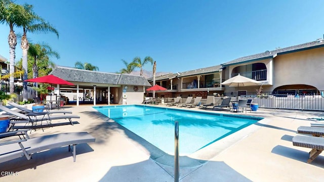 community pool with a patio area and fence