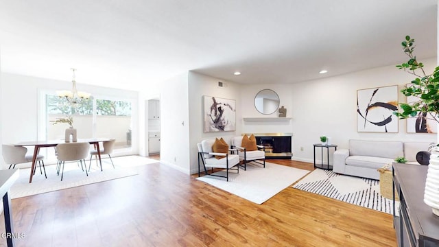 living area with a glass covered fireplace, baseboards, recessed lighting, and wood finished floors