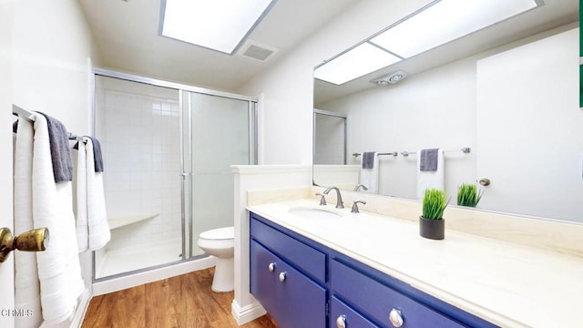 bathroom with toilet, a stall shower, wood finished floors, and vanity