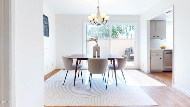 dining room with baseboards, light wood-type flooring, and an inviting chandelier