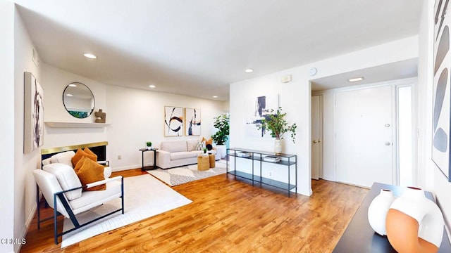 living area with recessed lighting, baseboards, a fireplace, and light wood finished floors