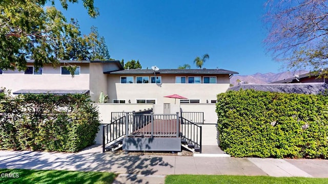 view of front of house featuring fence, a mountain view, and stucco siding