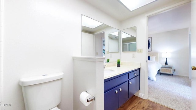 full bath featuring baseboards, toilet, wood finished floors, ensuite bathroom, and vanity