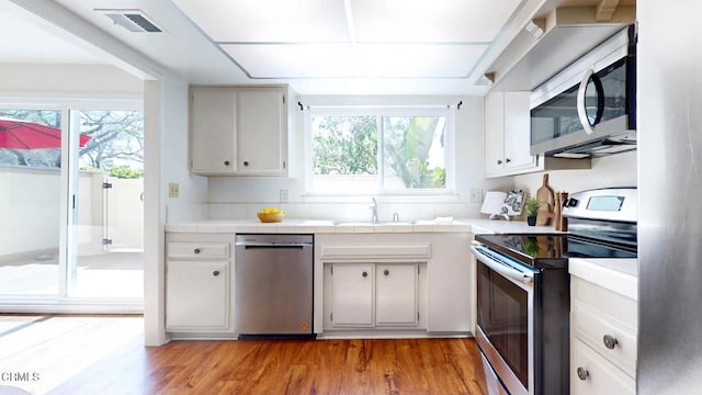 kitchen with a wealth of natural light, appliances with stainless steel finishes, a sink, and visible vents