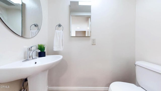 half bathroom featuring toilet and baseboards