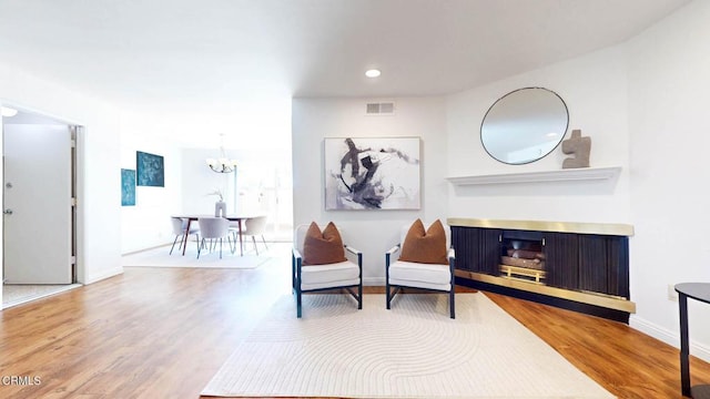 sitting room with a fireplace, wood finished floors, visible vents, and baseboards