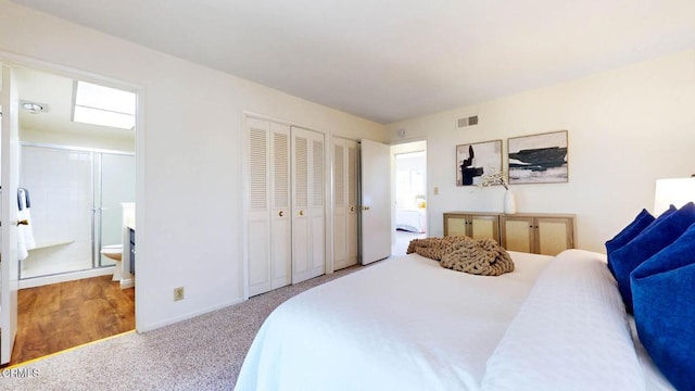 carpeted bedroom featuring visible vents, connected bathroom, and two closets