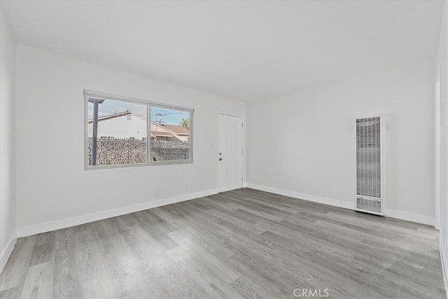 spare room with wood finished floors, visible vents, and baseboards