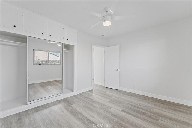 unfurnished bedroom featuring a closet, light wood-type flooring, a ceiling fan, and baseboards