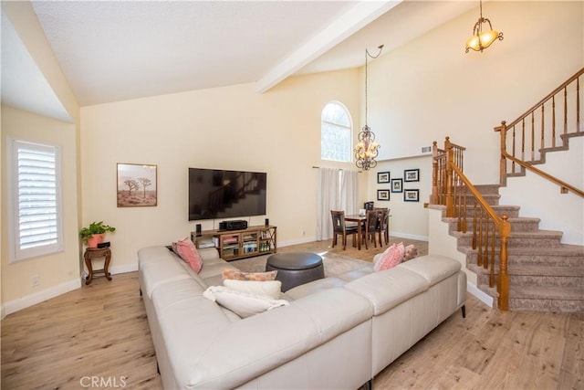 living room featuring a notable chandelier, light wood-style flooring, stairway, high vaulted ceiling, and baseboards