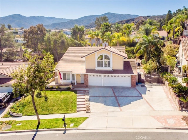 traditional-style home with brick siding, concrete driveway, a mountain view, a garage, and a tiled roof