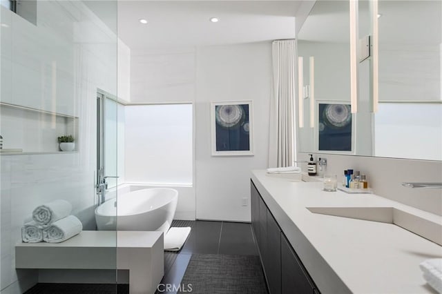 bathroom with double vanity, recessed lighting, a sink, tile patterned flooring, and a freestanding bath