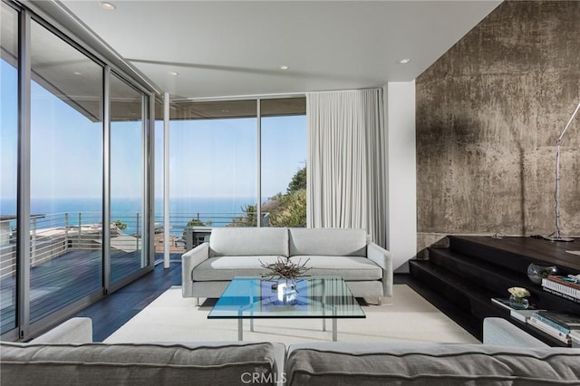 living area featuring a wall of windows, a water view, and wood finished floors