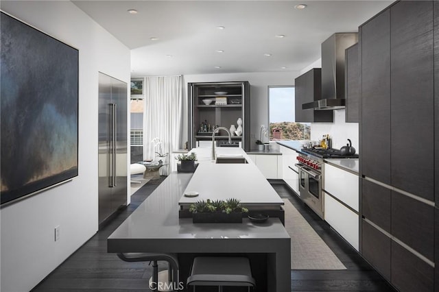 kitchen featuring modern cabinets, high end appliances, wall chimney range hood, and a sink