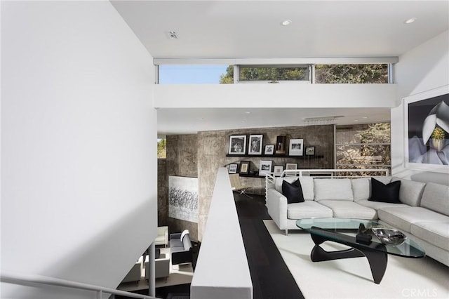 living room featuring an accent wall, a high ceiling, and a healthy amount of sunlight