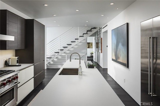 kitchen with dark wood-style floors, a sink, light countertops, modern cabinets, and premium appliances