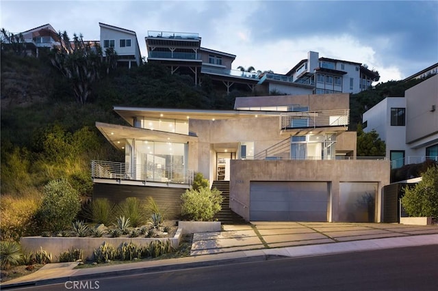 modern home with stucco siding, concrete driveway, stairs, and a balcony